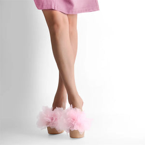 Pink tulle shoes worn with a pink skirt on a light gray background