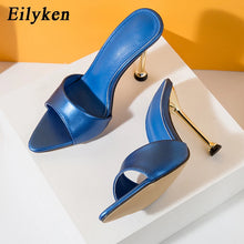 Load image into Gallery viewer, Blue high-heeled shoes with gold heels on a white platform against an orange background, featuring the brand 'Eilyken'.