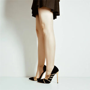 Black high-heeled shoes with gold accents worn by a person on a plain background