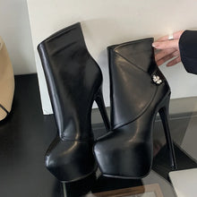 Load image into Gallery viewer, Black high-heeled platform boots on a reflective surface with a neutral background