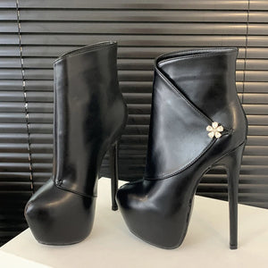 Black high-heeled platform boots with a decorative flower on a neutral background