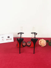 Load image into Gallery viewer, Black high-heeled shoes on a red platform with a white background