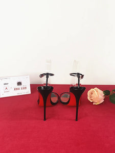 Black high-heeled shoes on a red platform with a white background