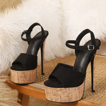 Load image into Gallery viewer, Black high-heeled sandals with cork platforms on a textured surface