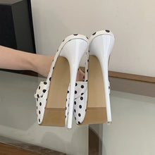 Load image into Gallery viewer, White high-heeled shoes with black polka dots being worn on a glass surface.