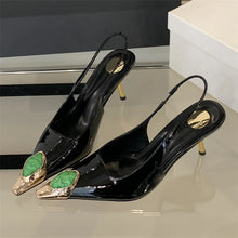 Load image into Gallery viewer, Black high-heeled shoes with gold and green accents on a reflective surface.