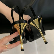 Load image into Gallery viewer, Black high-heeled shoes with gold soles held by a hand against a dark background