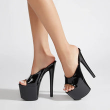 Load image into Gallery viewer, Black high-heeled platform shoes worn by a person on a light gray background