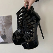 Load image into Gallery viewer, Black high-heeled shoes with platform sole held by a hand against a neutral background