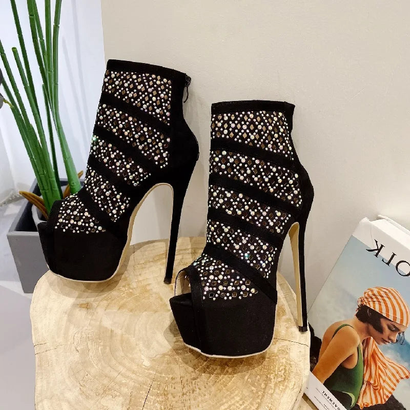 Black high-heeled shoes with rhinestone detailing on a wooden surface.