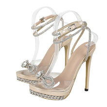 Load image into Gallery viewer, Beige high-heeled sandals with clear straps and rhinestone embellishments on a white background