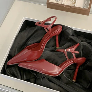 Red high-heeled shoes in an open box with a black interior.
