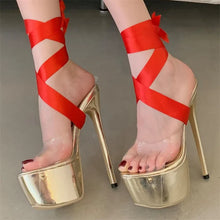 Load image into Gallery viewer, Gold high-heeled shoes with red ribbon straps on a neutral background