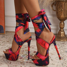 Load image into Gallery viewer, Colorful high-heeled shoes with floral pattern worn by a person indoors.