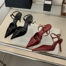 Load image into Gallery viewer, Black and red high-heeled shoes on a reflective surface with a magazine underneath.