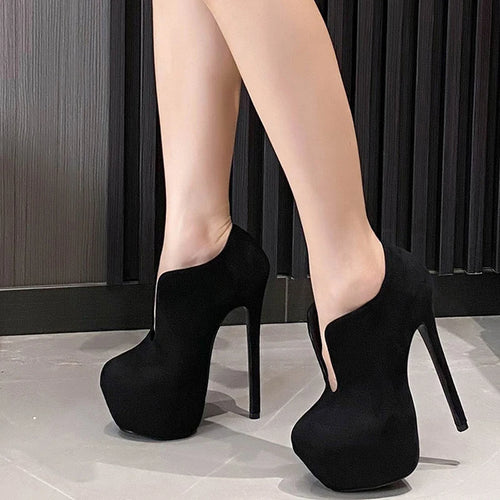 Black high-heeled shoes worn by a person on a neutral background