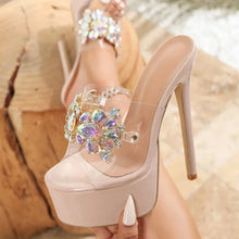 Load image into Gallery viewer, Beige high-heeled shoe with a decorative brooch held by a person.
