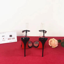 Load image into Gallery viewer, Black high-heeled shoes on a red surface with a white background