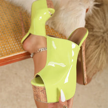 Load image into Gallery viewer, Lime green high-heeled shoes with cork sole worn by a person sitting on a chair.