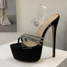 Load image into Gallery viewer, Black high-heeled shoe with clear strap and rhinestone details on a white platform.
