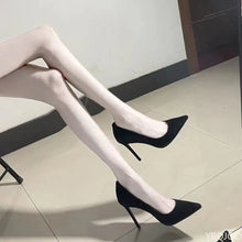 Load image into Gallery viewer, Black high-heeled shoes worn with white stockings on a light-colored floor.