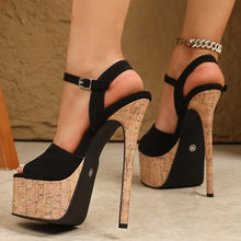 Load image into Gallery viewer, Black high-heeled platform shoes with cork sole worn by a person.