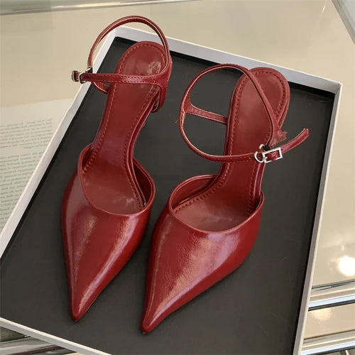 Pair of red high-heeled shoes on a black surface with a reflective background