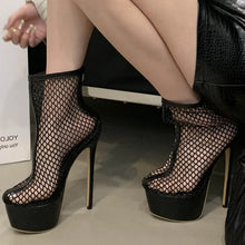 Load image into Gallery viewer, Black fishnet high-heeled platform shoes worn by a person sitting on a chair.