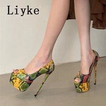 Load image into Gallery viewer, A person wearing a pair of high-heeled platform slingback shoes with a yellow, green, and red snakeskin pattern. The image shows the model's legs from the knees down, standing against a plain beige wall and concrete floor.