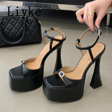 Load image into Gallery viewer, Black high-heeled platform shoes with a hand holding one shoe, on a neutral background.