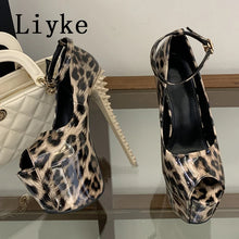 Load image into Gallery viewer, A pair of high-heeled platform sandals with a leopard print pattern, displayed on a glass shelf next to a white quilted handbag. The brand name 'Liyke' is visible in the top left corner.