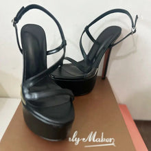 Load image into Gallery viewer, Black high-heeled shoes on a cardboard surface with &#39;Only Maker&#39; branding.