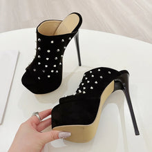 Load image into Gallery viewer, Black studded high-heeled shoes on a white surface with a hand holding one shoe.