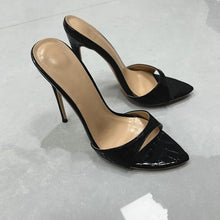 Load image into Gallery viewer, A pair of black pointed-toe high heels with a glossy crocodile-embossed texture and slim stiletto heels, shown on a light gray tiled floor.