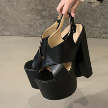 Load image into Gallery viewer, Black platform sandals held by a hand against a neutral background