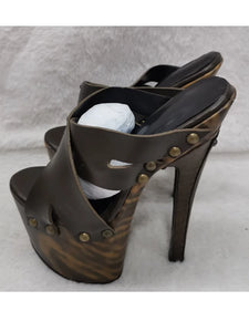 Brown high-heeled sandals with gold studs on a gray background